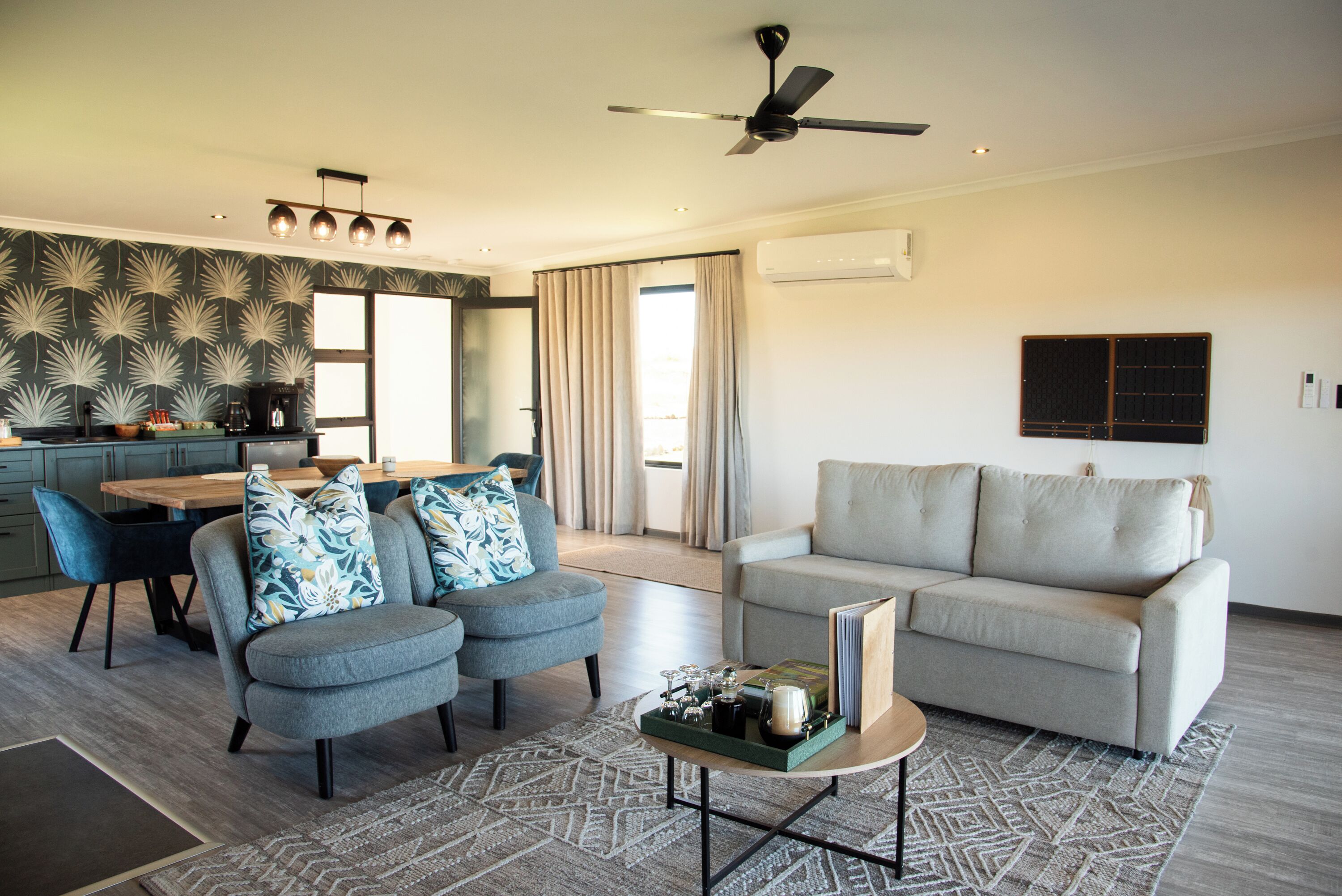 A modern living room with a sofa, a coffee table, and a dining area with a table and chairs.