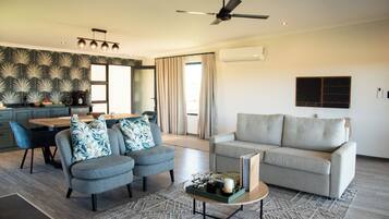 A modern living room with a sofa, a coffee table, and a dining area with a table and chairs.