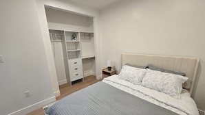 A bedroom with a bed, a nightstand, a wardrobe, and a built-in shelving unit. - Cozy Guesthouse Near Disneyland in Walking Distance (Garden Grove)