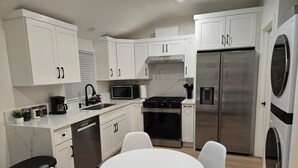 A modern kitchen with white cabinets, a stainless steel refrigerator, a microwave, and a gas stove. - Cozy Guesthouse Near Disneyland in Walking Distance (Garden Grove)