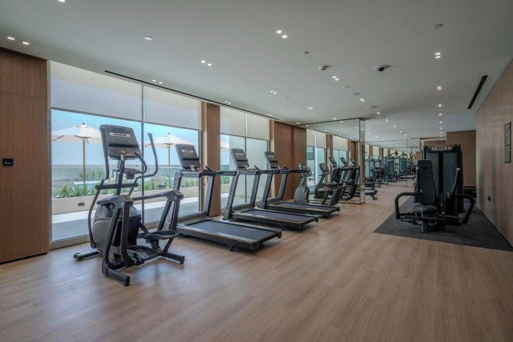 Une salle de sport équipée de tapis de course, de vélos elliptiques et de matériel de musculation.
