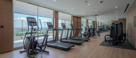 Une salle de sport équipée de tapis de course, de vélos elliptiques et de matériel de musculation.