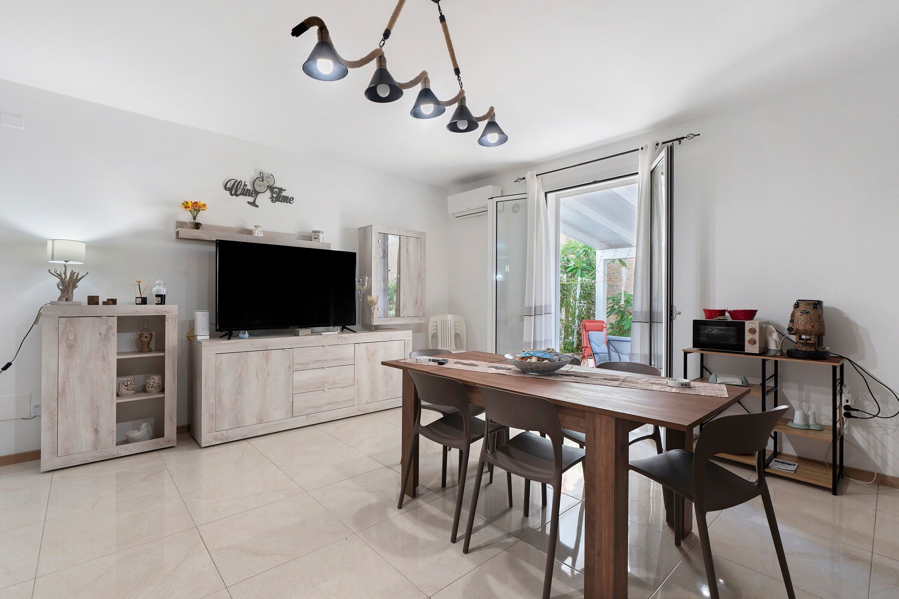Una cocina moderna con una mesa de comedor, sillas, un televisor y un microondas.