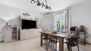 Una cocina moderna con una mesa de comedor, sillas, un televisor y un microondas.