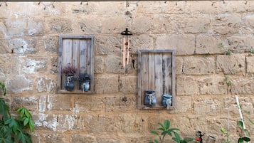 Una pared de piedra rústica con dos marcos de madera para ventanas, cada uno con una maceta.