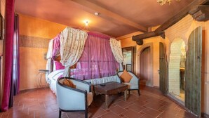 Una habitación con una cama, dos sillas, una mesita y una cama con dosel y cortinas.