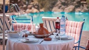 Mesa de comedor al aire libre con vistas a una piscina, sillas y una botella de agua.