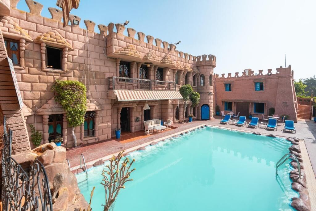 Ein schlossähnliches Gebäude mit Pool, Außenbereich und Balkon.