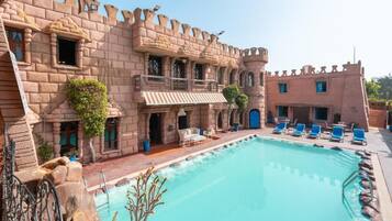 Ein schlossähnliches Gebäude mit Pool, Außenbereich und Balkon.