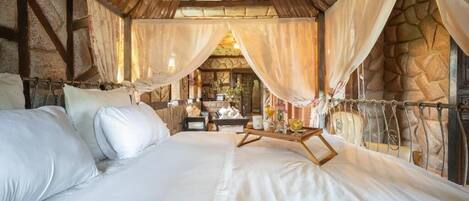 Ein Schlafzimmer mit Stehwand, einem großen Bett mit weißer Bettwäsche und einem Nachttisch aus Holz.
