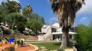 Una casa moderna con un camino de piedra, piscina y un jardín bien cuidado.