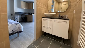 Un baño moderno con un lavabo tipo recipiente, un espejo redondo y un mueble blanco.