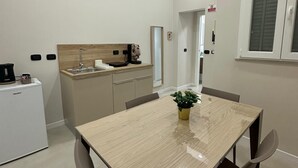 Eine moderne Küche mit Einbauofen, Spüle und Arbeitsplatte. Ein Esstisch mit Stühlen und ein Topf mit Pflanze sind ebenfalls vorhanden.