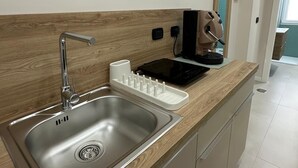 Eine Küche mit Spüle aus Edelstahl, einem eingebauten Mikrowellenherd und einer Holzarbeitsplatte.