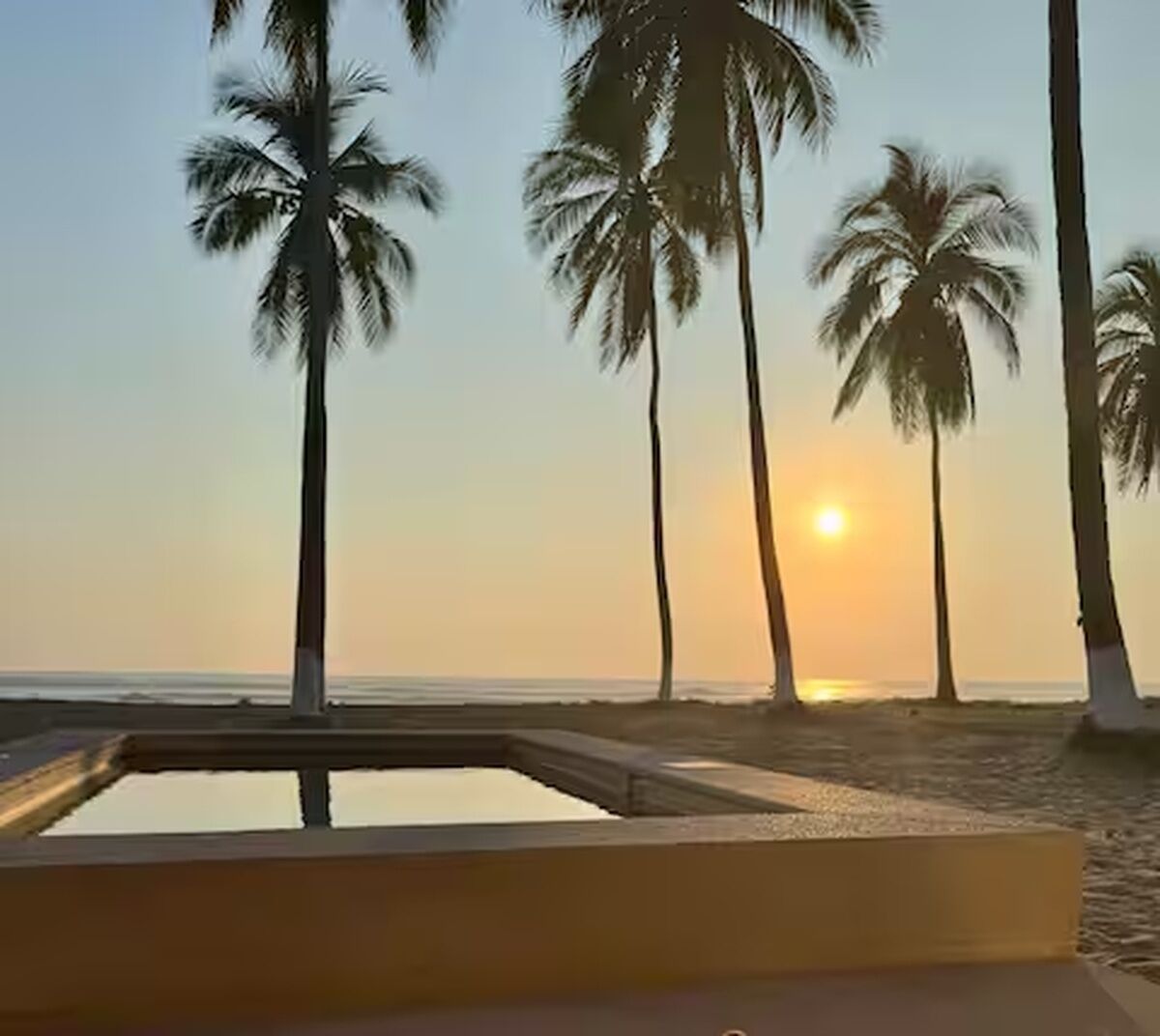 A beach scene with palm trees and a pool.
