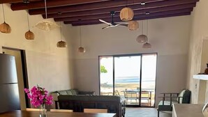 A spacious living area with a dining table, chairs, a sofa, and a view of the beach through a glass door. - Beachfront House with Private Pool, near Troncones (Gro.)