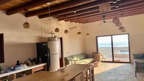 A spacious kitchen with a wooden table, a refrigerator, and hanging pendant lights. - Beachfront House with Private Pool, near Troncones (Gro.)