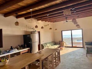 A spacious kitchen with a wooden table, a refrigerator, and hanging pendant lights. - Beachfront House with Private Pool, near Troncones (Gro.)
