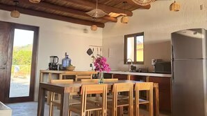 A kitchen with wooden beams, a dining table with chairs, a refrigerator, and hanging wicker light fixtures. - Beachfront House with Private Pool, near Troncones (Gro.)