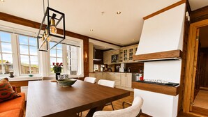 Une cuisine moderne avec un coin repas, un plancher en bois et une vue sur l’extérieur.