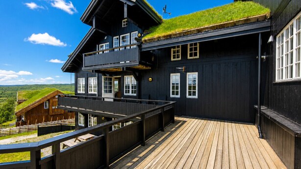 Un bâtiment à deux étages doté d’une terrasse en bois et d’un toit recouvert d’herbe.