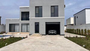 Una casa moderna de dos pisos con garaje, piscina y césped bien cuidado.