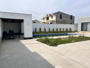 A building with a swimming pool, a covered outdoor area with tables and chairs, and a garage. - Big and comfortable villa (Shuvelan)