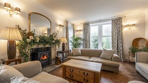 Ein gemütliches Wohnzimmer mit Kamin, Sofas, einem Couchtisch und einem großen Spiegel.
