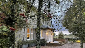 Ein Haus mit Naturstein-Fassade, einer Veranda und einem Schotterweg.
