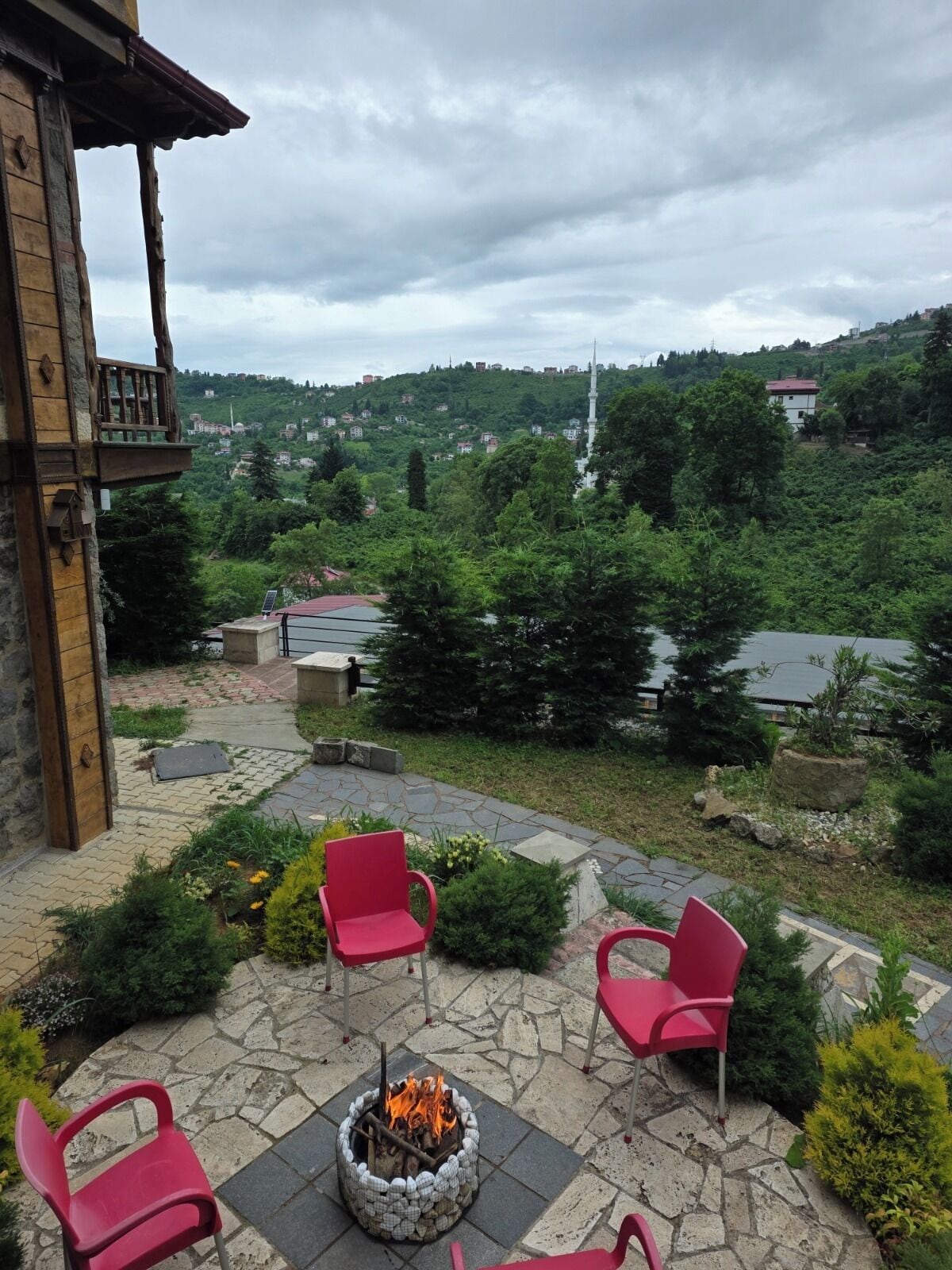 A patio with stone flooring, red chairs, and a fire pit.
