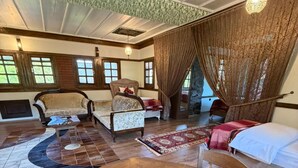 Una habitación amplia con una gran mesa redonda, dos sofás, una cama y una chimenea.