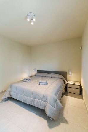 Ein Schlafzimmer mit einem Bett, Nachttischen und einer Deckenleuchte.