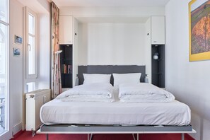 A bed with white linens, a radiator, a window, and a bookshelf. - Schone Ferienwohnung in Sellin mit Balkon (Sellin)
