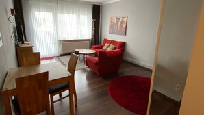 Un salon moderne avec un coin repas, un canapé rouge et un tapis rouge.