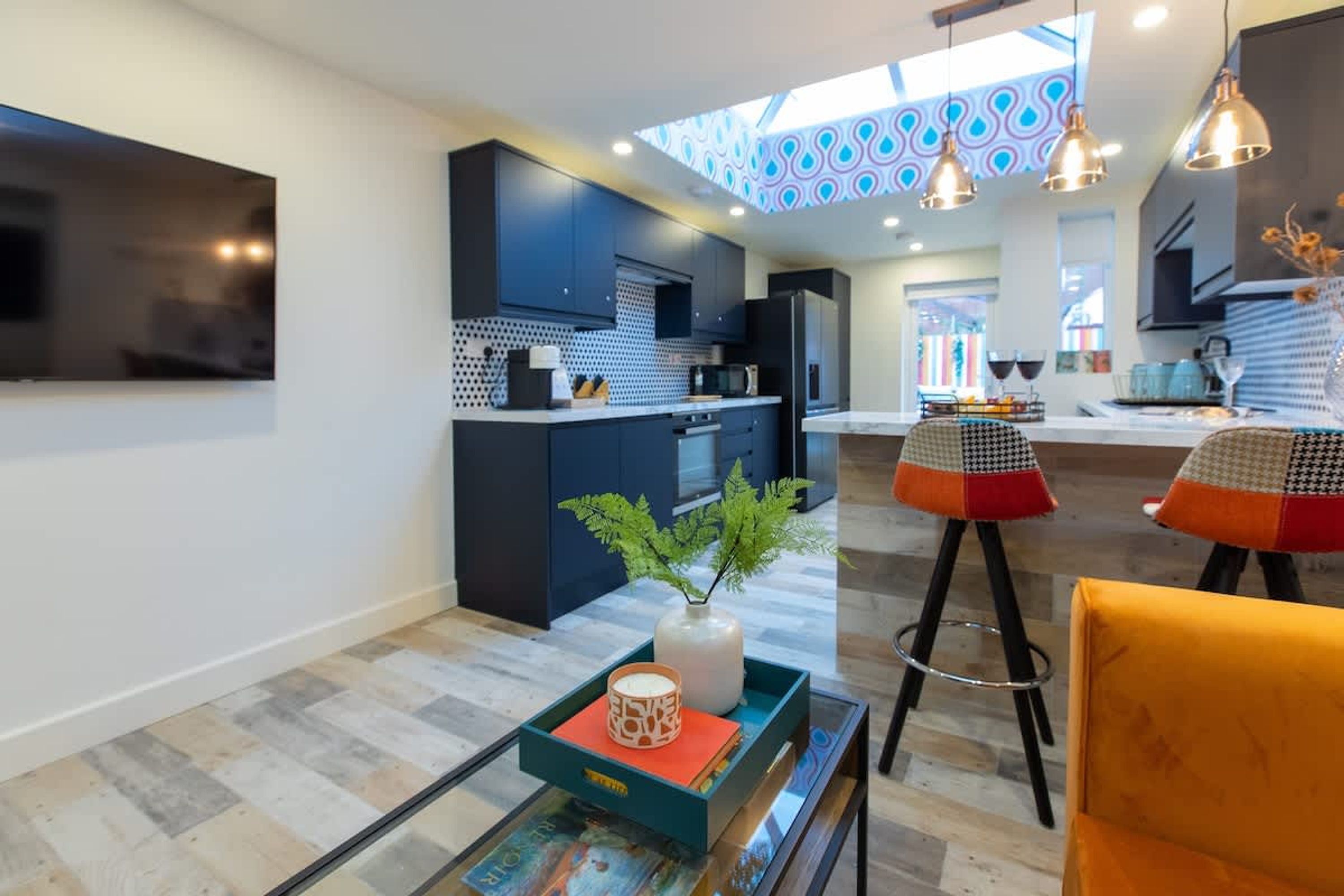 Una cocina moderna con armarios oscuros, un microondas y un comedor con mesa y sillas.