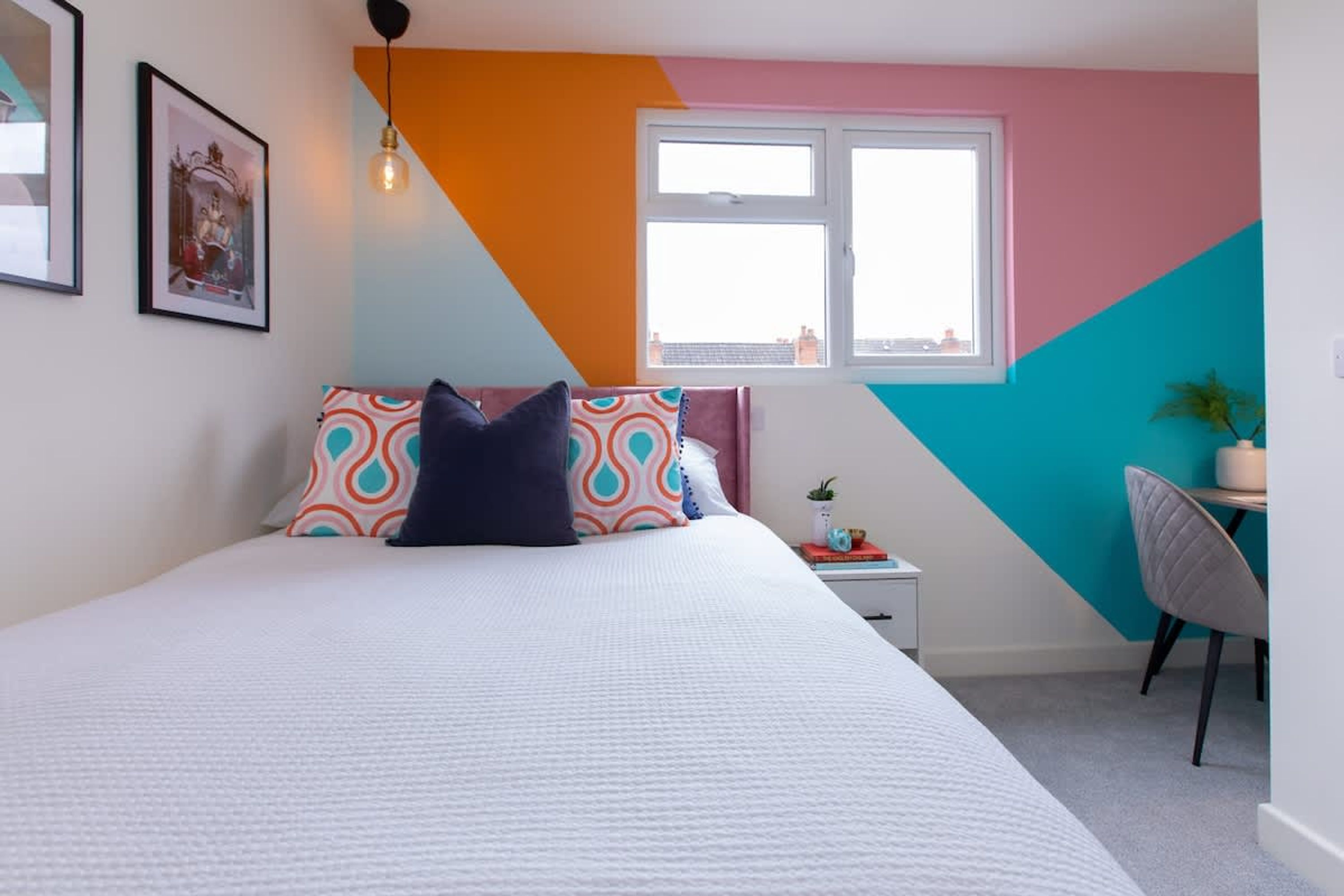 Ein Schlafzimmer mit Bett, Fenster, Schreibtisch und Stuhl.