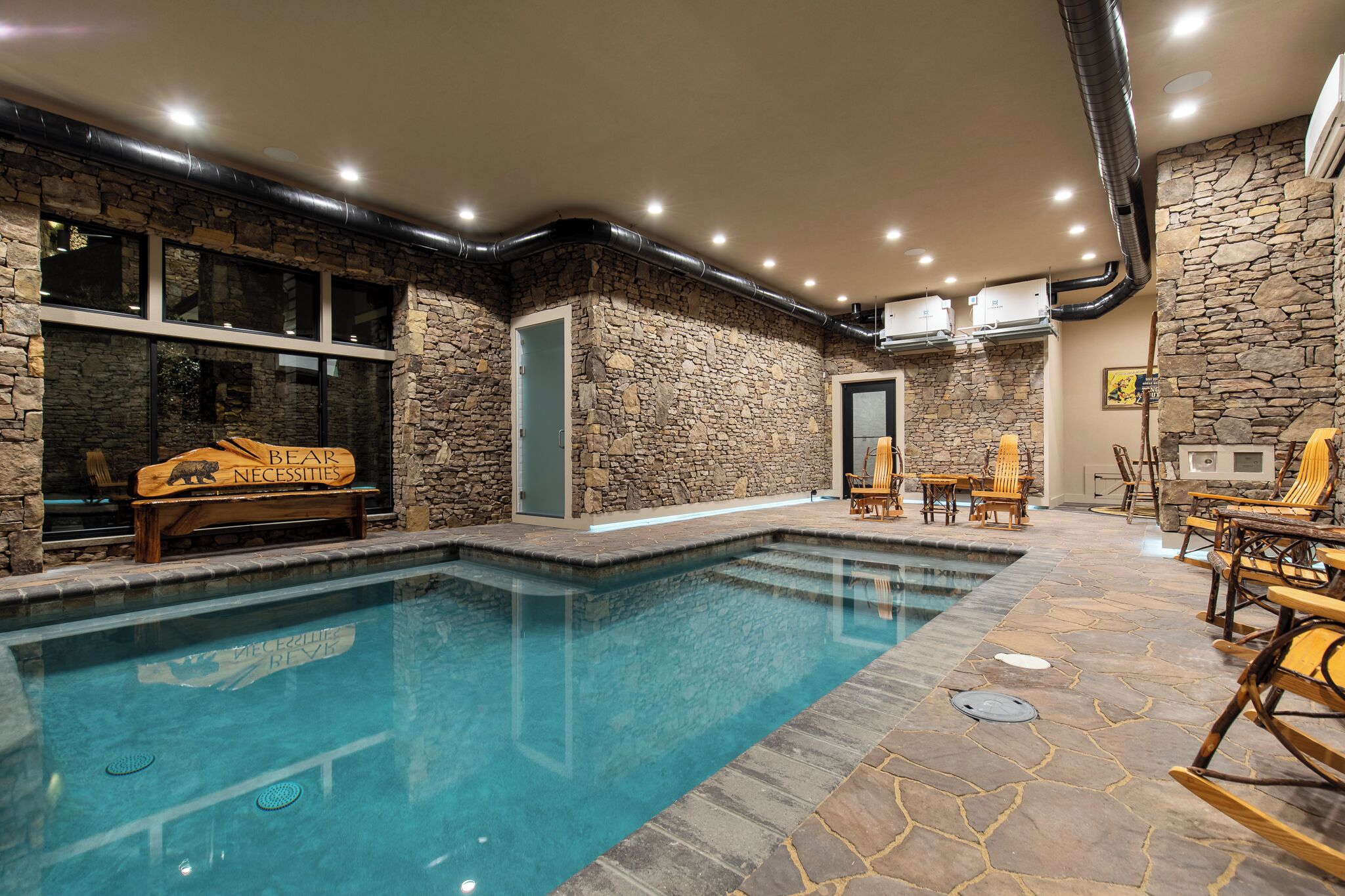 A pool area with stone walls, wooden furniture, and a bear sign.