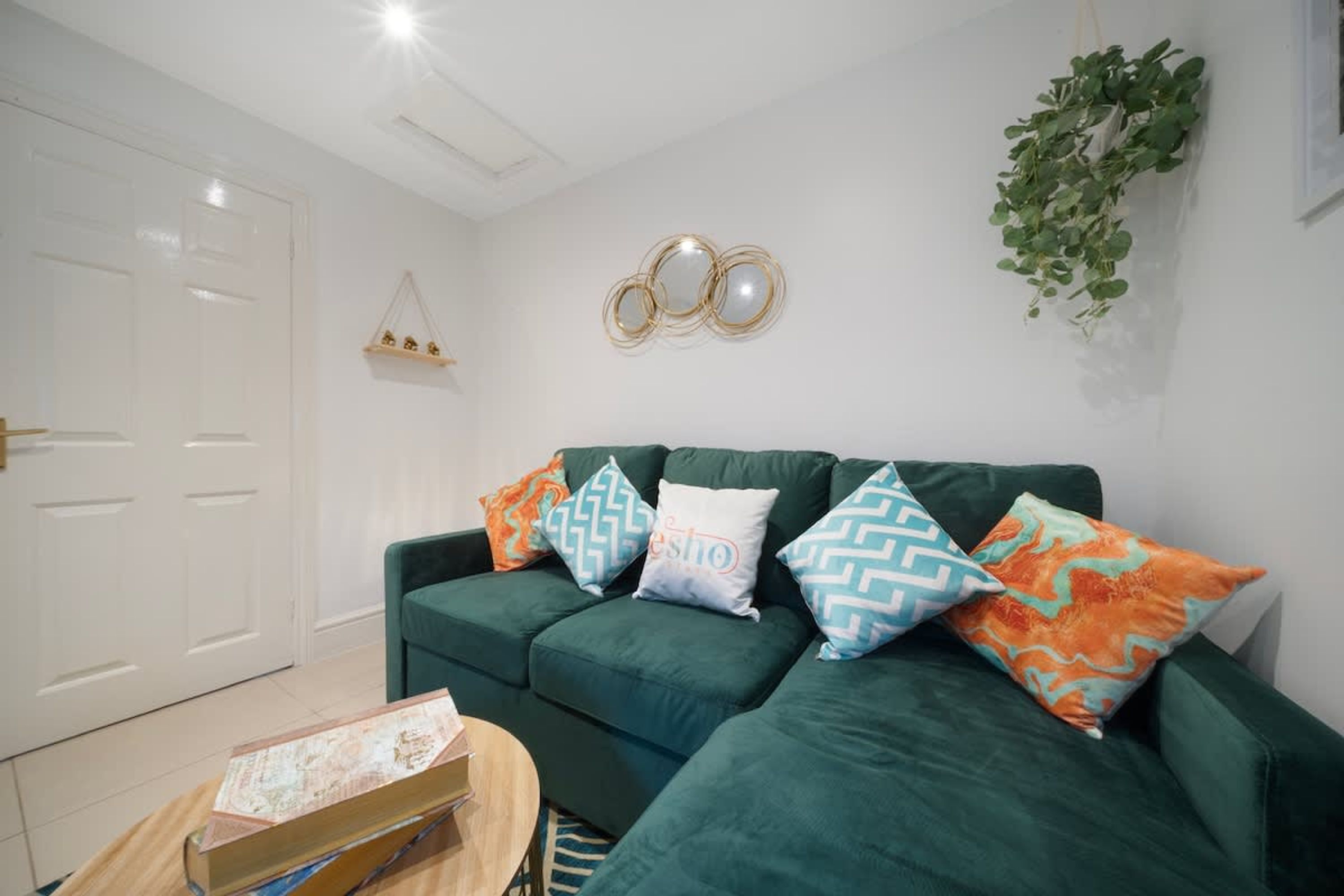 A green sofa with patterned cushions, a wooden coffee table, and a white door.