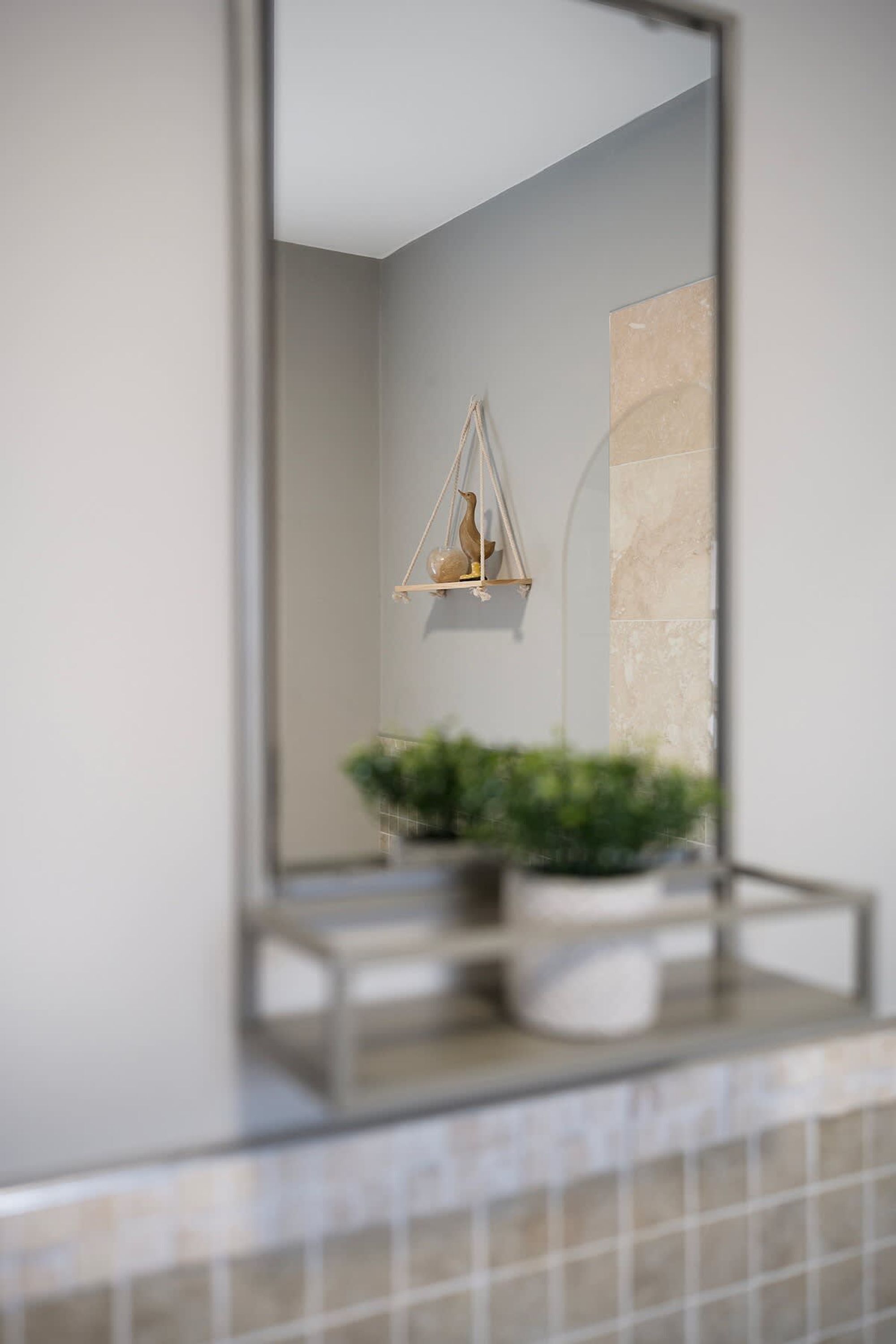 A bathroom with a mirror, a hanging light fixture, and a potted plant.