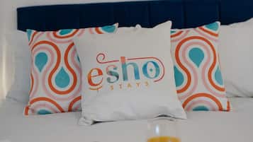 A bed with a blue headboard, two patterned pillows, and a tray with breakfast items.