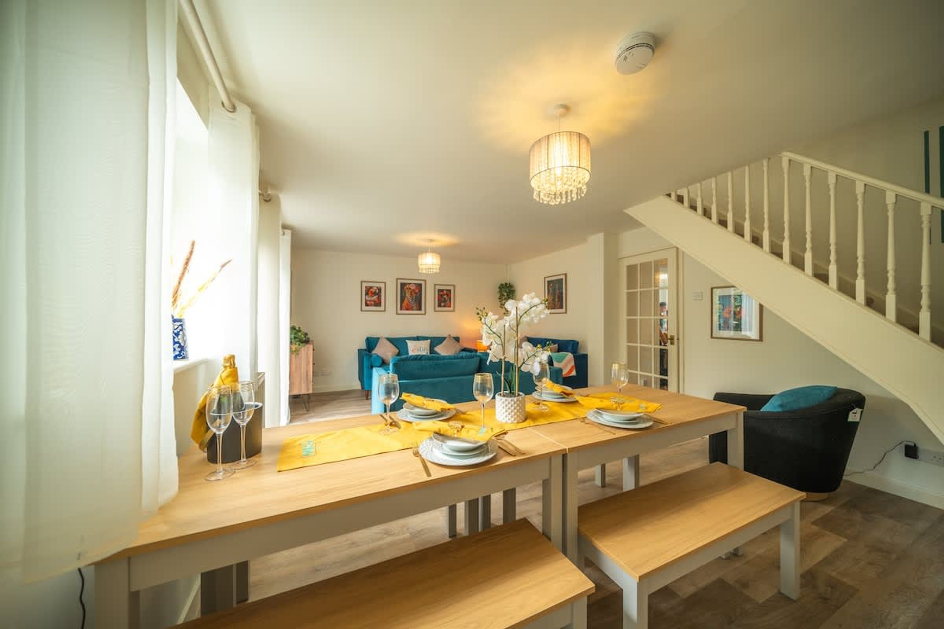 Un espace repas avec une table en bois, des bancs et un escalier.