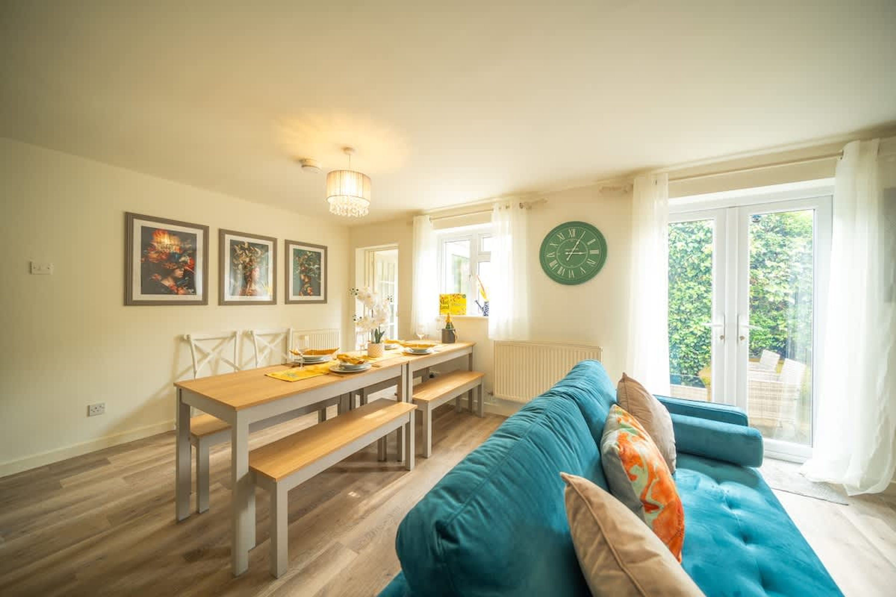 Un salon moderne avec un canapé bleu, une table à manger avec des bancs et une grande fenêtre avec des rideaux.