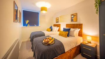 Een hotelkamer met twee bedden, een raam met uitzicht, een nachtkastje met lamp en een radiator.