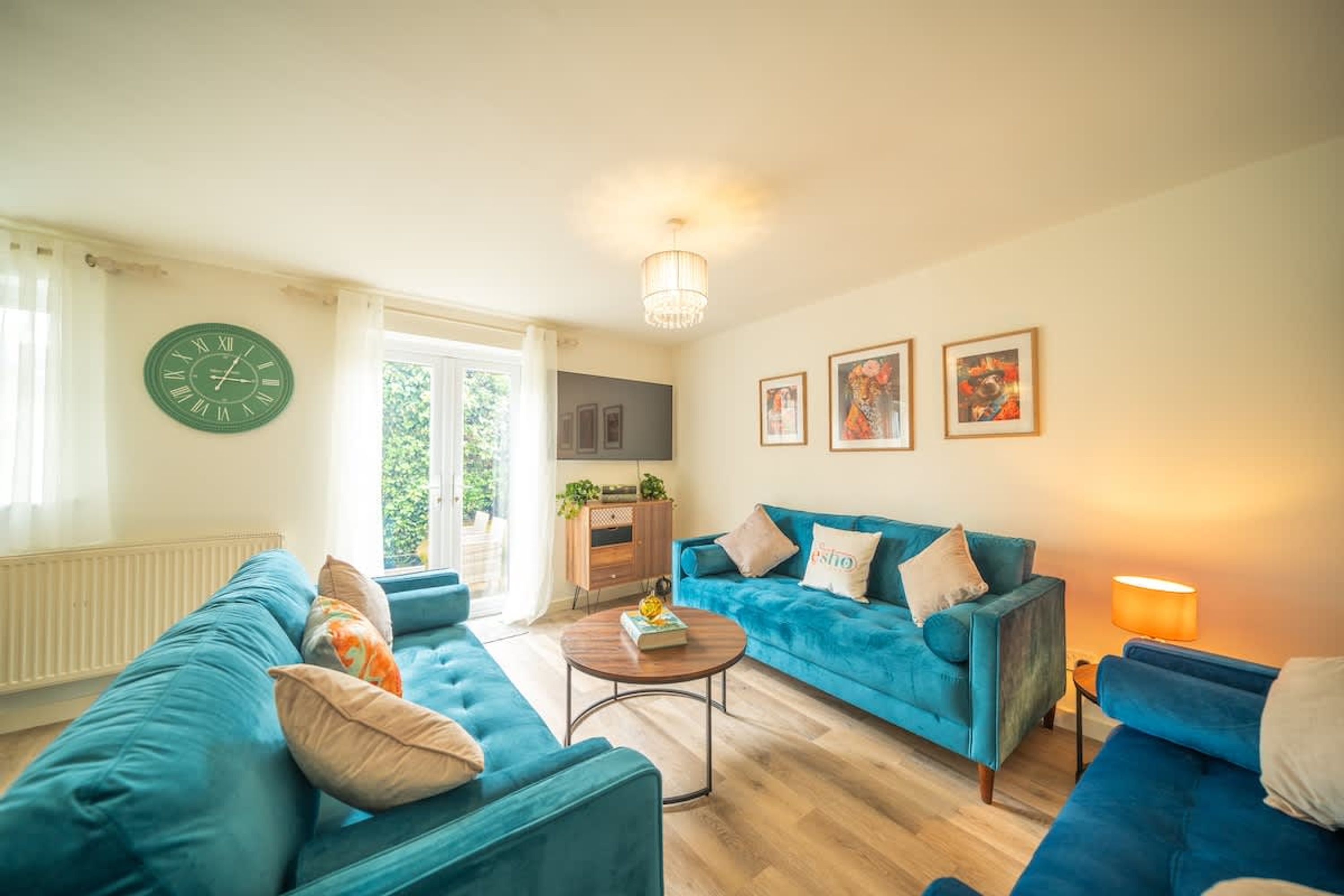 Een woonkamer met een blauwe bank, een ronde salontafel en een klok aan de muur.