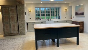 A modern kitchen with a large island, skylight, and a view of the outdoors. - Stunning Countryside House With Pool and Hot Tub (Malmesbury)