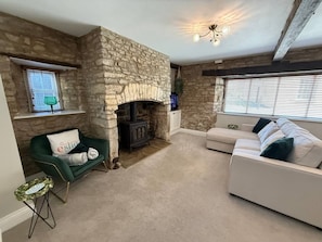 A stone fireplace, a green armchair, a white sofa, and a ceiling light fixture. - Ground Floor Apartment in 18th Century Building (Cirencester)