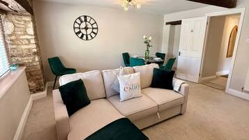 A living room with a sofa, a clock, a chandelier, and a dining area.