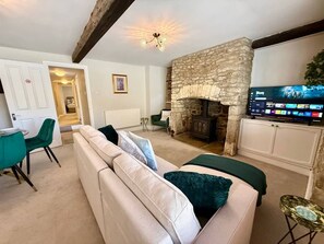 A living room with a stone fireplace, a television, a sofa, and a dining area. - Ground Floor Apartment in 18th Century Building (Cirencester)