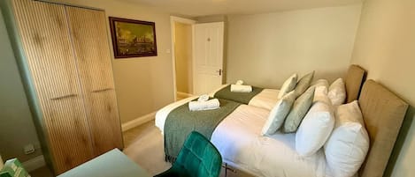 A hotel room with a bed, a desk, a chair, a wardrobe, and a door.