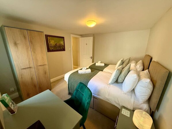 A hotel room with a bed, a desk, a chair, a wardrobe, and a door. - Ground Floor Apartment in 18th Century Building (Cirencester)